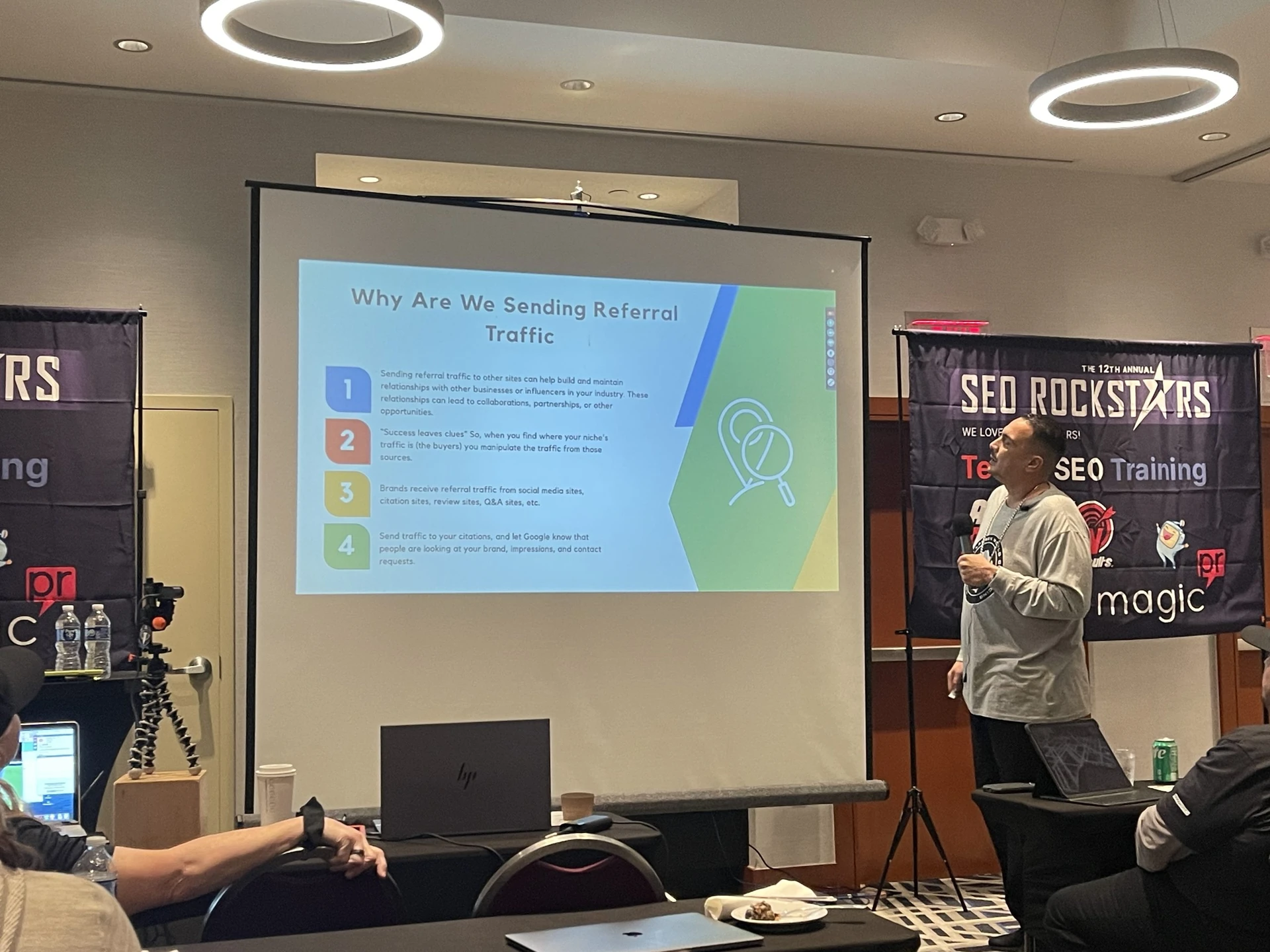 A conference presentation with attendees and SEO Rockstars banners.